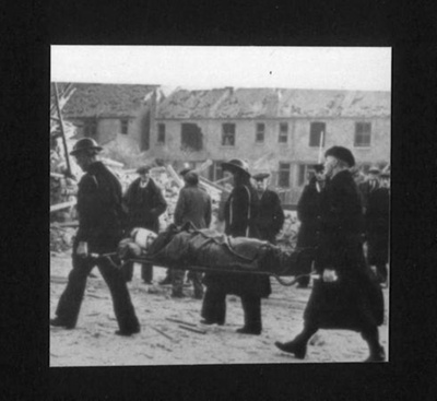 Photograph - casualty on stretcher being carried away from bombed building; 6844 Photograph - casualty on stretcher being carried away from bombed building; 6844