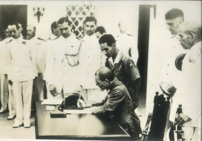 Photograph - Japanese Army Officers signing surrender document in view of Allied Naval Officers; 38040