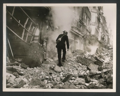 Official copyrighted war photograph- 11th October 1940- policeman inspecting damage near a bomb crater; 56531