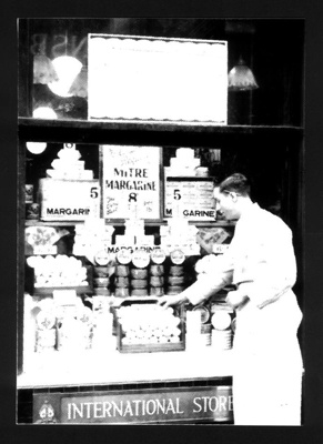 Photograph - shopkeeper in war-time outside "International Store" - margarine on display; 1812 Photograph - shopkeeper in war-time outside "International Store" - margarine on display; 1812