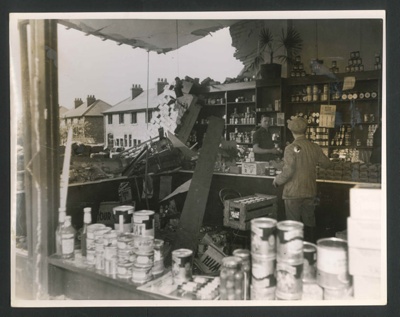Official copyrighted war photograph- 28th August 1940- workmen clearing foodstuffs from damaged shop in the north-west; 56549