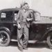 Photograph of Richard William Hutchinson-Hopper stood next to vehicle at Eden Camp. Possible camp warden; 78132