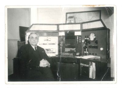 Photograph - person unknown - sitting in front of a control desk; 36358