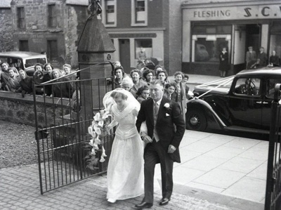 fht.2026.116  wedding at high church, mid 50's, with background 34-36 high street, taylor's jewellers,38-40, labour party office, 42, scws butcher and draper.