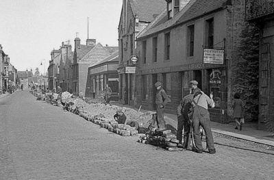 fht.2026.114  view of forres high street in 1947, with pipelaying in progress in front of brander's fruiterer at no 50 and reid's china shop at no 48.