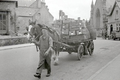 fht.2026.107  sandy grant, lorryman with wordie and co, with his horse and cart and dog, at the bridge street end of the high street, circa 1958.