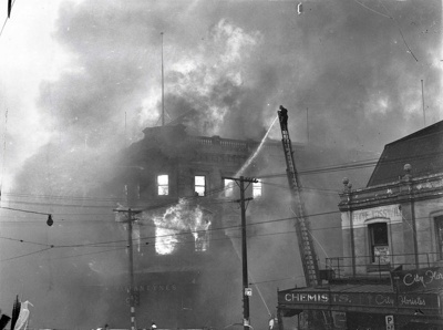 Ballantyne's Fire. Fireman up Turntable Ladder Directing Water at the Colombo Street and Cashel Street Corner of the Building. Christchurch, Canterbury, New Zealand. 10 image item