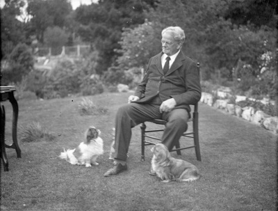 Man, Seated in Suburban Garden with Dogs, Christchurch. Canterbury, New Zealand. image item