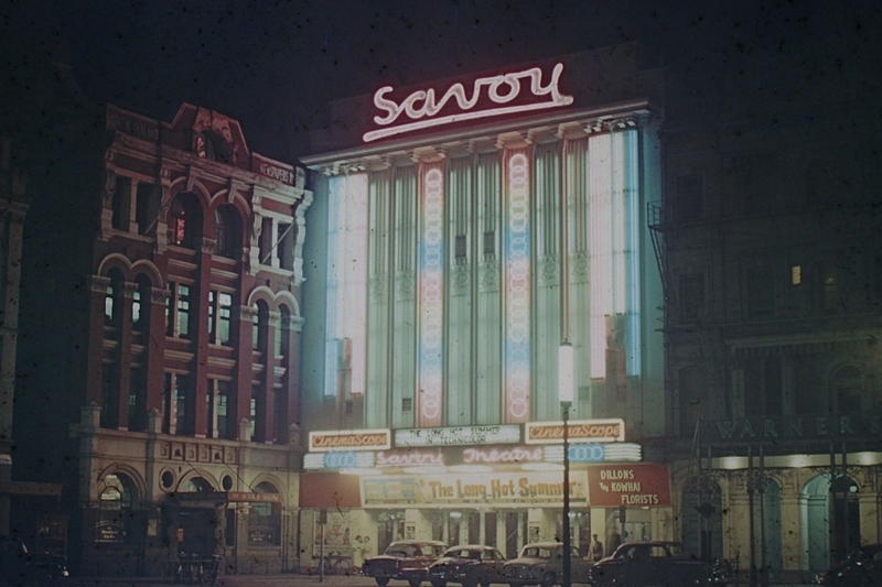 Theatre. The Savoy Theatre, Formerly the Liberty. Lit Up with Neon Lights at Night. The Film THe Long Hot Summer was an American drama film starring Paul Newman, Joanne Woodward, Anthony Franciosa, and Orson Welles, It was made in 1958. The Star-Sun Newspaper Building is on the Left and Warners Hotel on the Right. Cathedral Square, Christchurch, Canterbury. New Zealand.