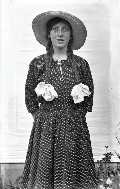 Young Woman Posing. Dressed in a Polka Dot Dress. A Straw Hat and with Plaits Tied off with Ribbons. Christchurch, Canterbury, New Zealand.