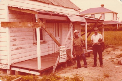 Arthur White and Nelson Blake outside Brindle Cottage after its arrival at the Howick Historical Village.; La Roche, Alan; December 1977; P2021.34.02
