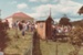 A crowd of people at Howick Historical Village during a Live Day. In the foreground is the Witch's house.; August 1983; P2021.172.04