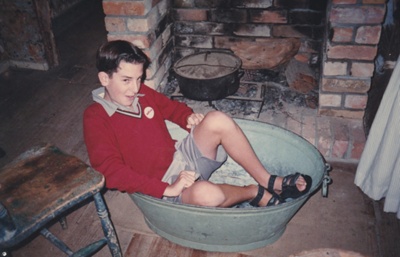 A schoolboy sitting in a tin bath at Historical Village during a school visit.; c1990; P2021.185.02