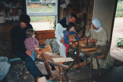 A guide, in costume, demonstarting making shingles on a shaving horse, on a Live Day in Howick Historical Village.; La Roche, Alan; P2021.98.06