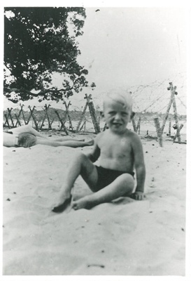 Max Farquharson sitting on the sand at Takapuna Beach; c1940; 2016.554.63