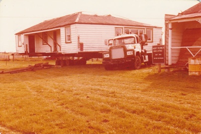 A transporter positioning Eckford's homestead on site at Howick Historical Village. ; La Roche, Alan; 14 June 1978; P2021.09.21