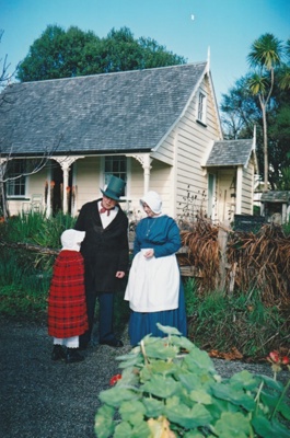 Doug White and a woman with a little girl outside Sergeant Barry's cottage in Howick Historical Village. All in costume.; La Roche, Alan; P2020.143.07