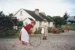 Two girls in costume, one playing with a hoop outside Briody-McDaniel cottage on a Live Day in Howick Historical Village.; La Roche, Alan; P2021.129.06