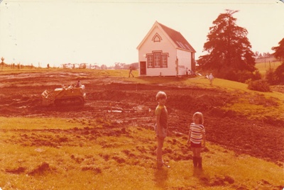 Philip and Maria la Roche in front of a bulldozer digging out the pond in the Howick Historical Village in front of Pakuranga School.; La Roche, Alan; 21 April 1979; P2022.19.10