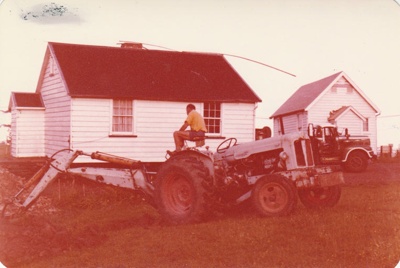 John Litten on a tractor clearing the site for McDermott's Cottage at Howick Historical Village.
; La Roche, Alan; 19 December 1974; P2020.100.11