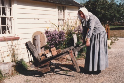 Adrienne Zuppicisch outside Briody's cottage carting bricks on a brick barrow.; P2021.105.26