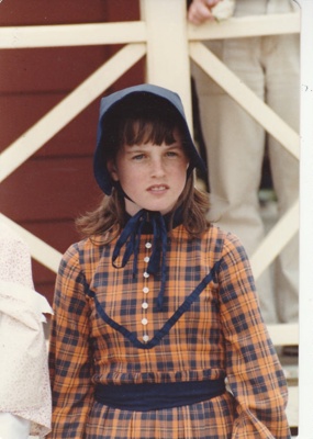 A girl in costume standing outside de Quincey's Cottage on a Gala day at Howick Historical Village.; Healey, N; October 1985; P2021.179.02