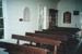 The interior of Howick Methodist Church at the Howick Historical Village, showing the pews at the rear of the church, a cabinet and wall placques.; La Roche, Alan; P2020.40.09