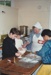 Three boys helping a Village guide with baking in Pakuranga School in the Howick Historical Village.; P2020.64.08