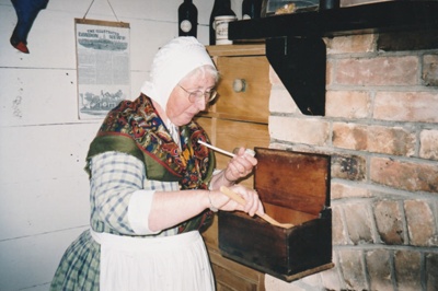 Lois Abram, in costume looking at the pipe collection in Howick Historical Village.; P2021.105.17