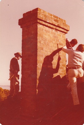 Men dismantiling the chimney on the roof of Eckford's homestead before removal to the Howick Historical Village. ; La Roche, Alan; 6 May 1978; P2021.09.16