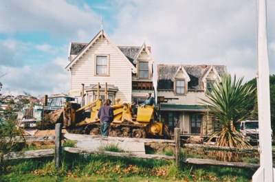A bulldozer and a Johnson's truck in front of Puhinui on its new site in the Howick Historical Village.; Alan La Roche; May 2002; P2020.11.15
