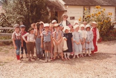 Rosemary McLean with a class, all in costume outside Briody-McDaniels Cottage, formerly McDermott's Cottage at Howick Historical Village.

; March 1984; P2020.101.06