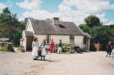 Two girls carrying a bucket of water in front of Briody-McDaniel cottage. ; 22 August 2006; 2019.196.04