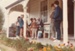 Visitors are watching two women  in costume spinning on the verandah of Sergeant Barry's cottage. at Howick Historical Village during the 1080 Gala in October 1984.; La Roche, Alan; October 1984; P2021.173.28