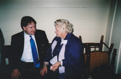 Dee Collings, a foundation member talking to an unnamed man at the 50th anniversary celebration of the Howick and Districts Historical Society in Bell House.; La Roche, Alan; 20 May 2012; P2022.27.15