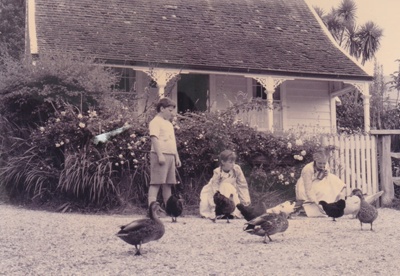 Children playing with chickens and ducks outside Sergeant Barry's cottage  in the Howick Historical Village.; La Roche, Alan; P2020.131.07