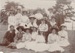 18 men and women together on the grass, posed for a photograph. Probably the Hattaway family.; P2021.166.09