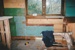Puhinui kitchen before restoration, showing bare walls, a window, sawhorse and debris.; Alan La Roche; May 2002; P2020.14.07