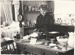 Mrs M Mills. a Fencible descendant demonstrating kitchen utensils at the 1962 exhibition of the Howick Historical Society in the Howick Town Hall.; Auckland Star; 1962; P2022.10.03