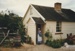Jane Martinson holding a baby, in costume outside Briody-McDaniels Cottage, formerly McDermott's Cottage at Howick Historical Village.

; La Roche, Alan; 1997; P2020.101.08