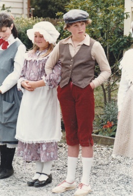 Two girls and a boy in costume standing outside de Quincey's Cottage on a Gala day at Howick Historical Village.; Healey, N; October 1985