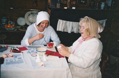 Sue Popping (Education) and Margaret Robinson in costume, making Christmas decorations in Briody-McDaniel Cottage.

; La Roche, Alan; c2002; P2020.104.02