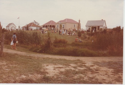 Looking across the pond to crowds of people around the cottages.; La Roche, Alan; 1983; 2019.109.02