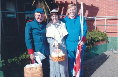 Alan la Roche, Coralie Nelson and Wally Rice (the men in Fencible uniform) holding the Union Jack outside the Howick Library in Uxbridge Road. ; October 2013; P2021.119.01