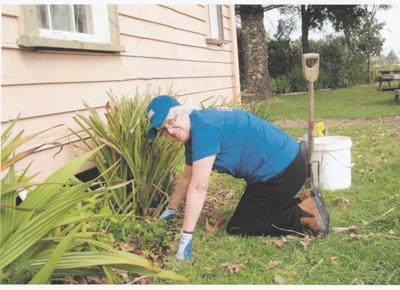 A BNZ worker weeding in front of a cottage in Howick Historical Village on BNZ staff volunteer day.; 4 September 2013; P2021.160.03