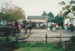 Celebrating Queen Victoria's birthday at Howick Historical Village. Showing a horse drawn carriage on the left, people with umbrellas on the right and others sheltering on the verandah of Brindle Cottage.; 21 May 1995; P2021.96.04