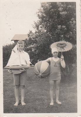Robert (Bob)Hattaway holding a model yacht and his sister, either Gwenyth or Shirley hilding a beach ball and parasol.; P2021.164.08