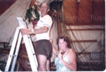 Photo: Two visitors hanging Christmas wreath on Endeavour yardarm; 97/1593