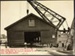 Photograph: Shed removal by floating crane from Quay Street Jetty No. 3 to west side of Central Wharf, shed being lowered onto skids on Central Wharf, 1917.; Auckland Harbour Board. Engineer's Dept.; 2010.132.252