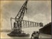 Photograph: Floating crane upending pile driver frame, 1913.; Auckland Harbour Board. Engineer's Dept.; 2010.132.225
